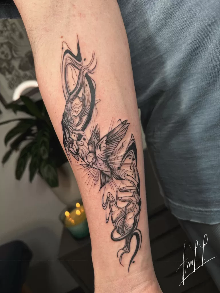 Swirl tattoo of hand releasing bird on arm fineline