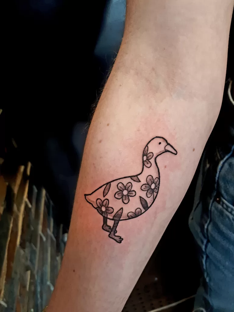 Cute duck with flowers tattoo in black and grey.