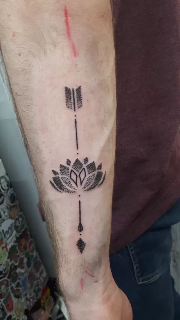 Pointillism arrow and lotus tattoo on forearm