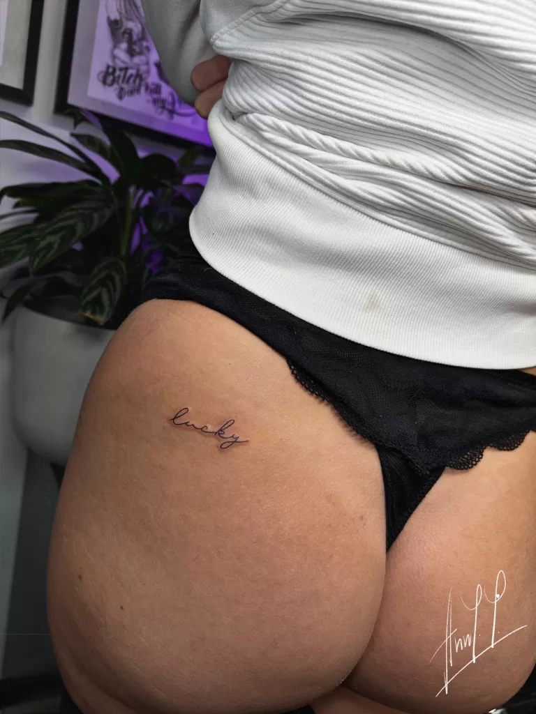 Fineline tattoo of script that says "lovely"