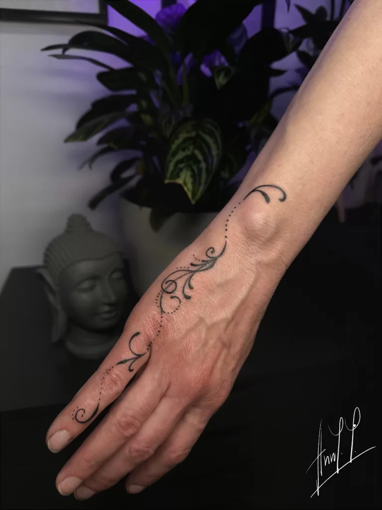 delicate filigree tattoo with dots on wrist to finger.