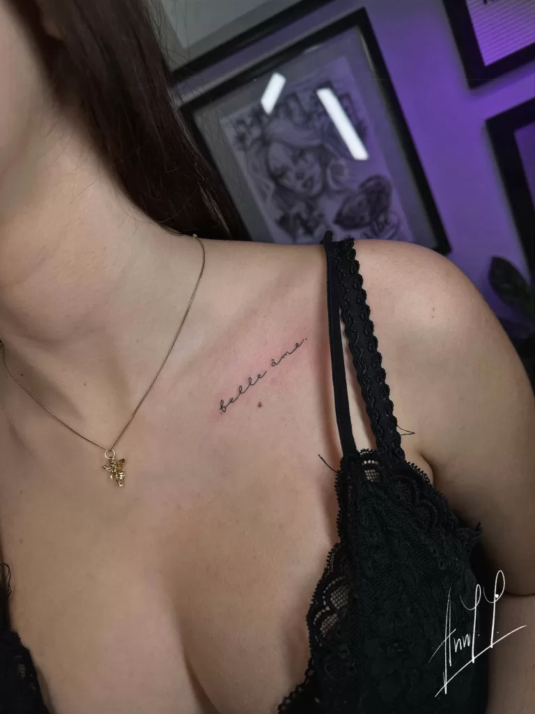 Simple fineline tattoo that says "belle ame" in french on collarbone.