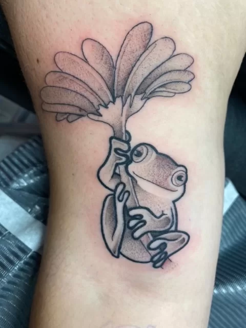 cute frog hanging on flower tattoo